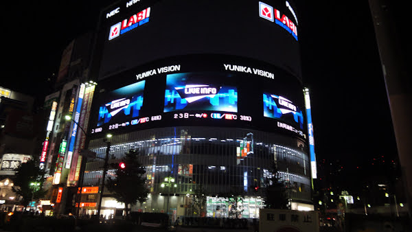 large screens on a building show videos